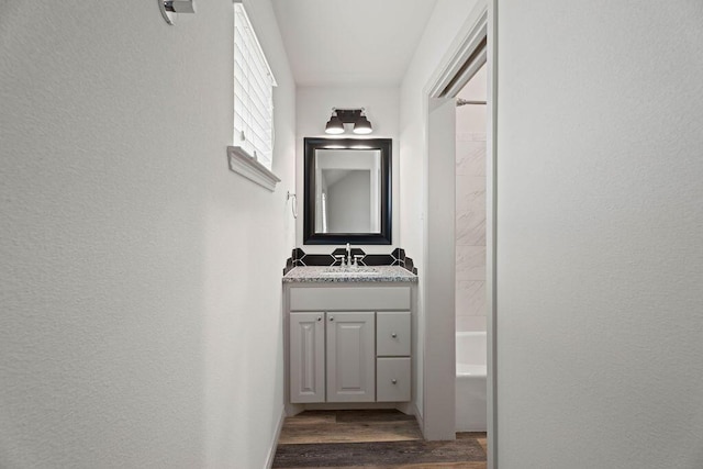 hall with a textured wall, dark wood finished floors, and a sink