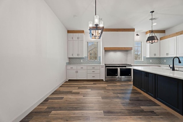 kitchen featuring dark wood-style floors, light countertops, decorative backsplash, white cabinets, and double oven range