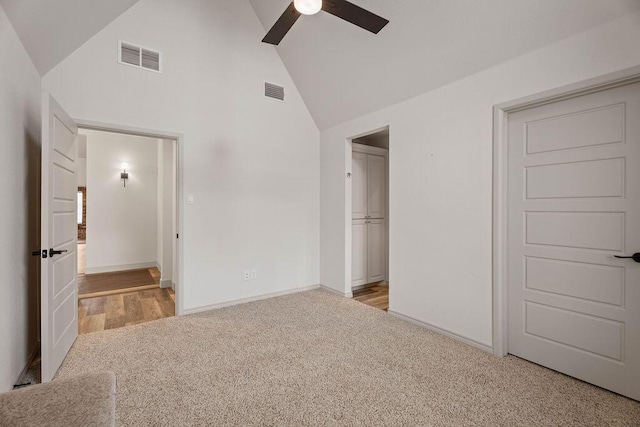 unfurnished bedroom with high vaulted ceiling, baseboards, visible vents, and light colored carpet