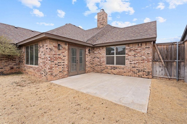 rear view of house featuring a patio area, french doors, brick siding, and roof with shingles