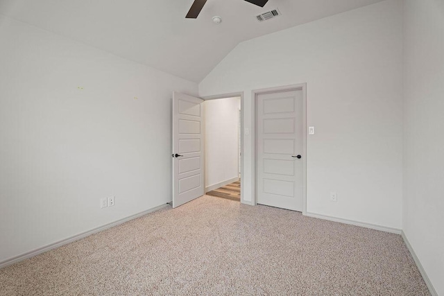 carpeted empty room featuring lofted ceiling, ceiling fan, visible vents, and baseboards