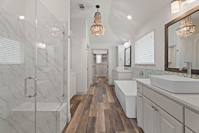 full bath with a stall shower, a chandelier, a freestanding tub, and a sink