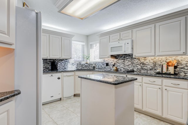 6910 Freeport Ave, Lubbock, TX 79424 - kitchen featuring white appliances, decorative backsplash, a center island, light tile patterned flooring, and dark stone countertops
