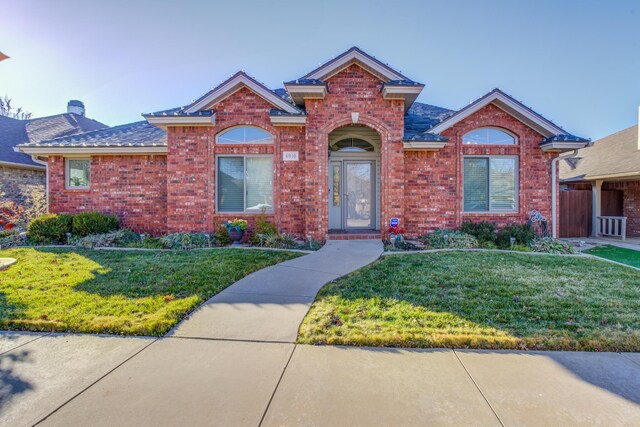 6910 Freeport Ave, Lubbock, TX 79424 - traditional home featuring brick siding, a front yard, a chimney, and a shingled roof