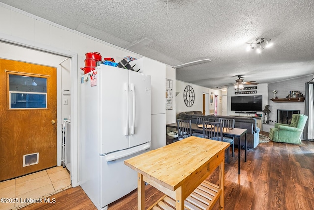 4411 58th St, Lubbock, TX 79414 - kitchen with freestanding refrigerator, a ceiling fan, a textured ceiling, and wood finished floors