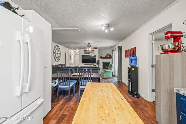 4411 58th St, Lubbock, TX 79414 - dining area with a ceiling fan, a textured ceiling, dark wood finished floors, ornamental molding, and a fireplace