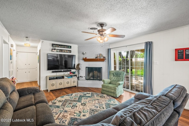 4411 58th St, Lubbock, TX 79414 - living area with ceiling fan, dark wood-style floors, a brick fireplace, and a textured ceiling