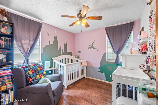 4411 58th St, Lubbock, TX 79414 - bedroom with a textured ceiling, wood finished floors, a ceiling fan, and a crib