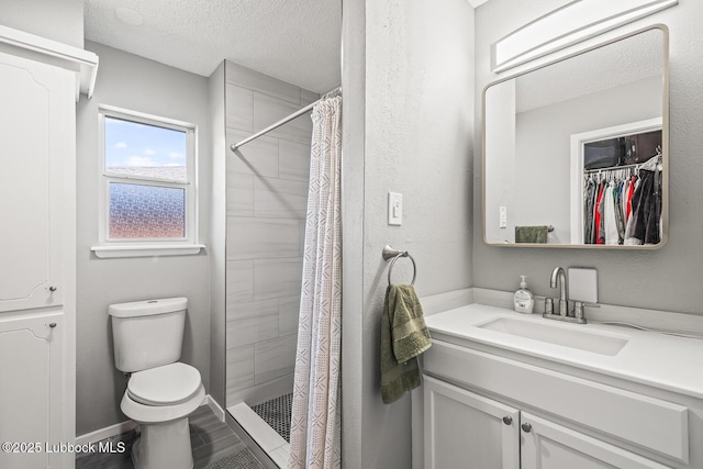 4411 58th St, Lubbock, TX 79414 - full bath featuring vanity, a textured ceiling, a stall shower, and a walk in closet