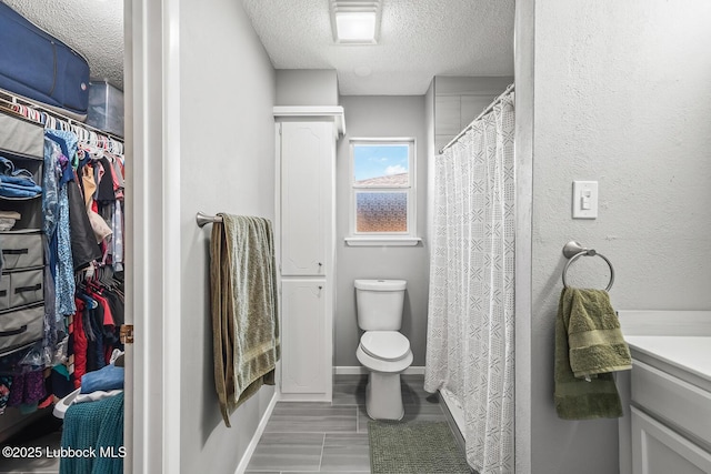 4411 58th St, Lubbock, TX 79414 - bathroom with a textured ceiling, vanity, and a walk in closet