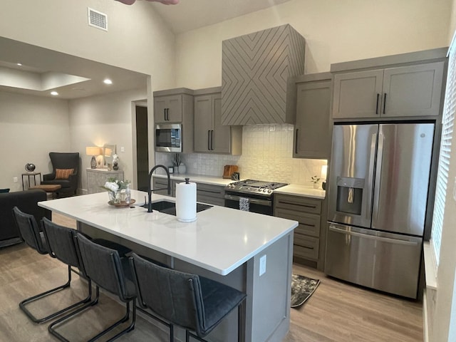 kitchen with sink, a breakfast bar area, gray cabinets, and appliances with stainless steel finishes