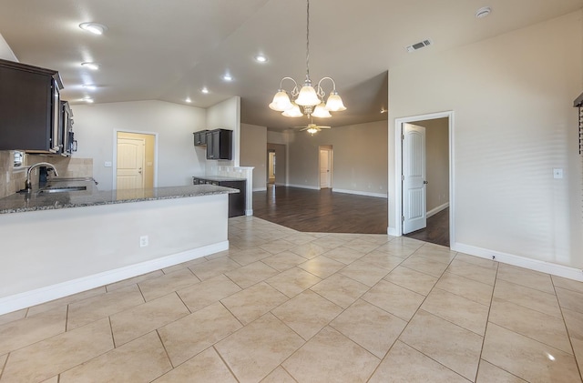 kitchen with pendant lighting, stone countertops, sink, and backsplash