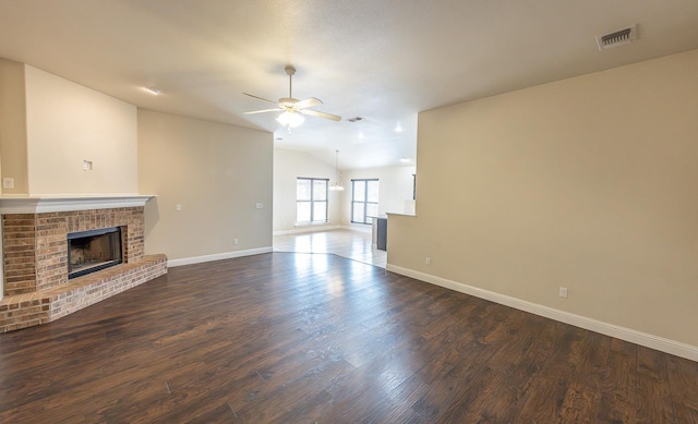 unfurnished living room featuring dark hardwood / wood-style flooring, a brick fireplace, vaulted ceiling, and ceiling fan