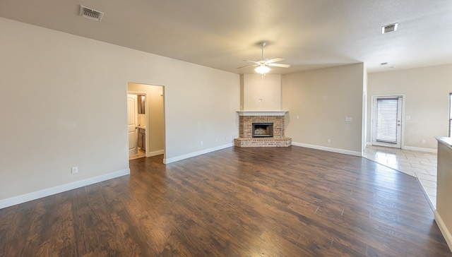 unfurnished living room with ceiling fan, dark wood-type flooring, and a fireplace