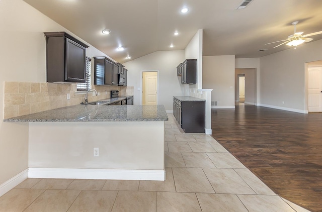 kitchen featuring sink, stainless steel electric range oven, light tile patterned floors, kitchen peninsula, and light stone countertops