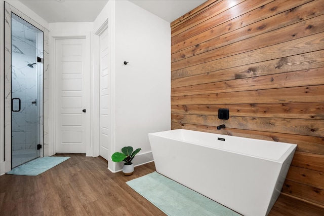 bathroom featuring wood-type flooring, wooden walls, and separate shower and tub