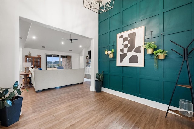 living room with hardwood / wood-style floors, ceiling fan, and a high ceiling