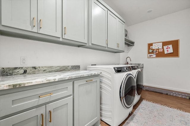 laundry room with dark wood-type flooring, washer and clothes dryer, and cabinets