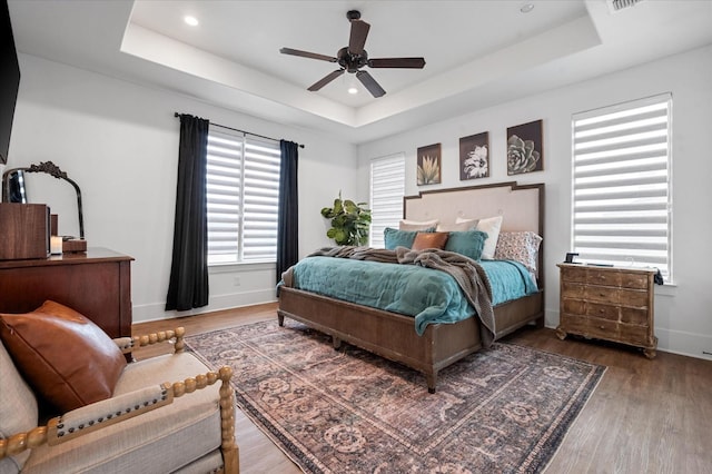 bedroom featuring ceiling fan, a raised ceiling, and hardwood / wood-style floors