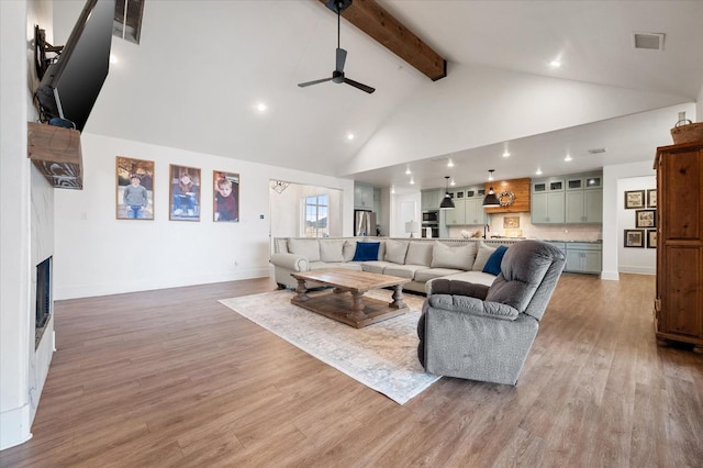 living room with ceiling fan, beam ceiling, high vaulted ceiling, and light hardwood / wood-style flooring