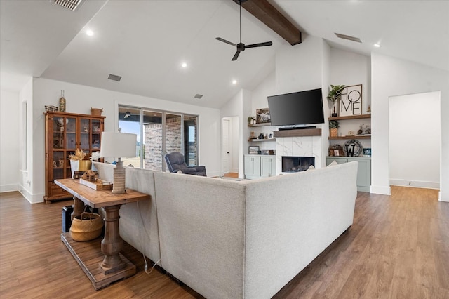 living room with hardwood / wood-style flooring, high vaulted ceiling, a fireplace, and beam ceiling