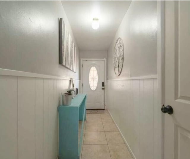 doorway to outside with a wainscoted wall and light tile patterned floors