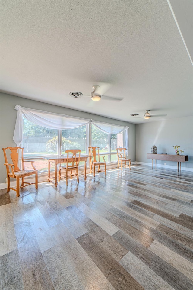 unfurnished dining area featuring ceiling fan, light hardwood / wood-style flooring, and a textured ceiling