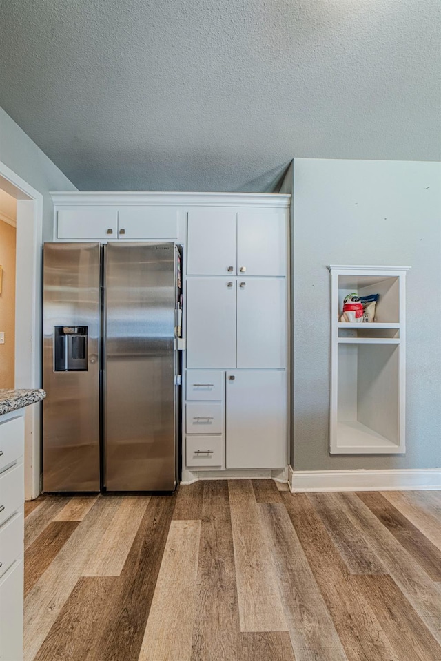 kitchen with white cabinetry, stainless steel fridge, and light hardwood / wood-style flooring