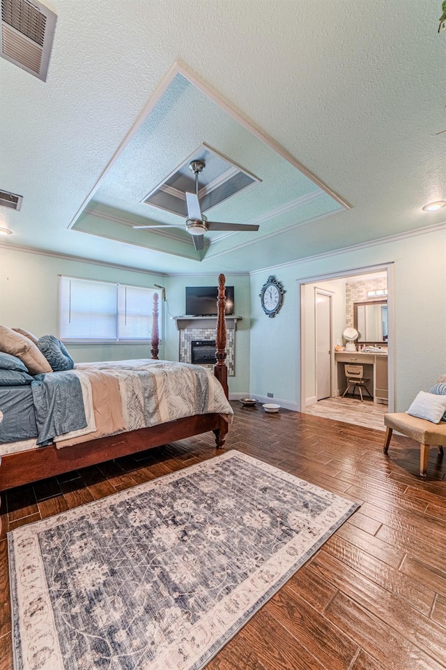 bedroom with crown molding, hardwood / wood-style flooring, a raised ceiling, and a textured ceiling