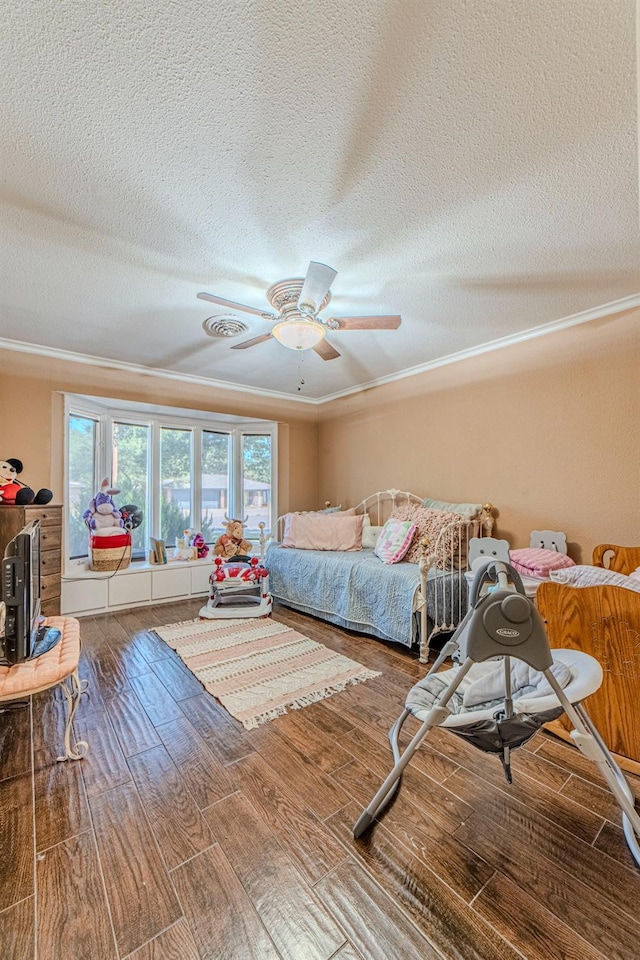 bedroom featuring hardwood / wood-style flooring, ornamental molding, ceiling fan, and a textured ceiling