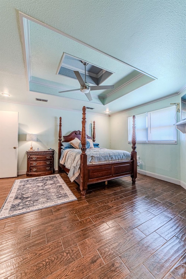 bedroom featuring crown molding, dark hardwood / wood-style floors, a textured ceiling, and a tray ceiling