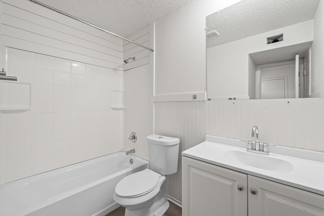 full bathroom featuring vanity, tiled shower / bath, toilet, and a textured ceiling