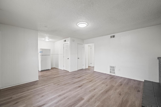 unfurnished living room with a textured ceiling and light hardwood / wood-style floors