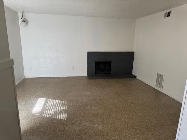 unfurnished living room with a brick fireplace and a textured ceiling