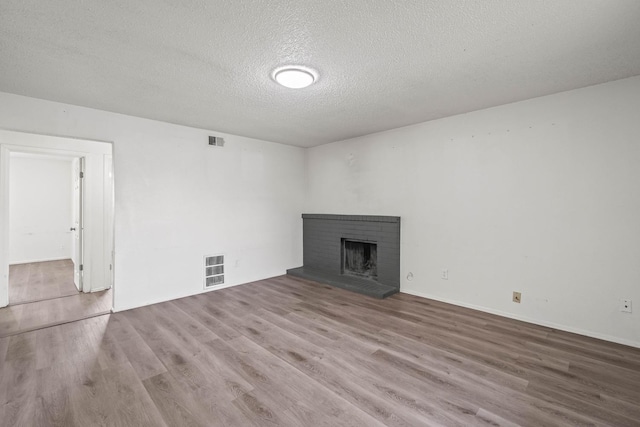 unfurnished living room featuring light wood-type flooring, a textured ceiling, and a fireplace