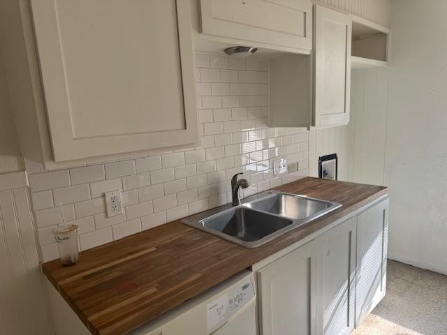 kitchen featuring white cabinetry, sink, backsplash, and wood counters