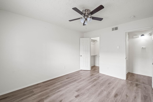 unfurnished bedroom featuring ceiling fan, a textured ceiling, light hardwood / wood-style floors, and a closet