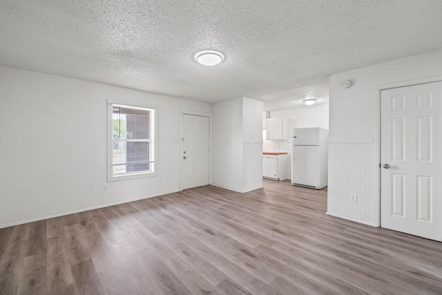 unfurnished living room featuring light hardwood / wood-style flooring and a textured ceiling