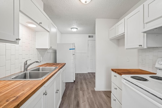 kitchen featuring white appliances, wood counters, sink, and white cabinets