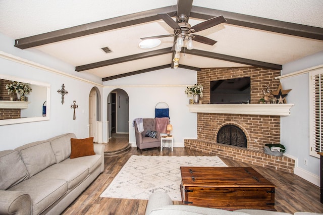 living area with wood finished floors, visible vents, arched walkways, lofted ceiling with beams, and ceiling fan