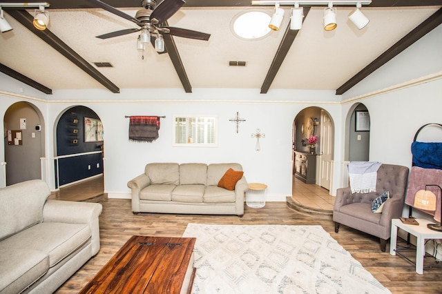 living area with baseboards, visible vents, arched walkways, and ceiling fan