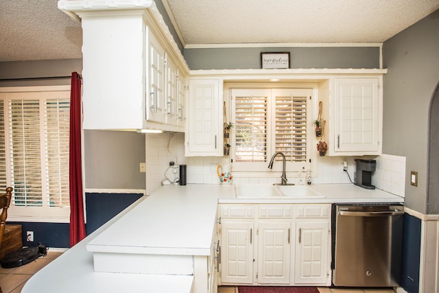 kitchen featuring stainless steel dishwasher, backsplash, a sink, and a textured ceiling