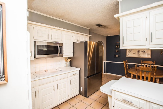 kitchen with stainless steel appliances, a textured ceiling, visible vents, light countertops, and light tile patterned floors
