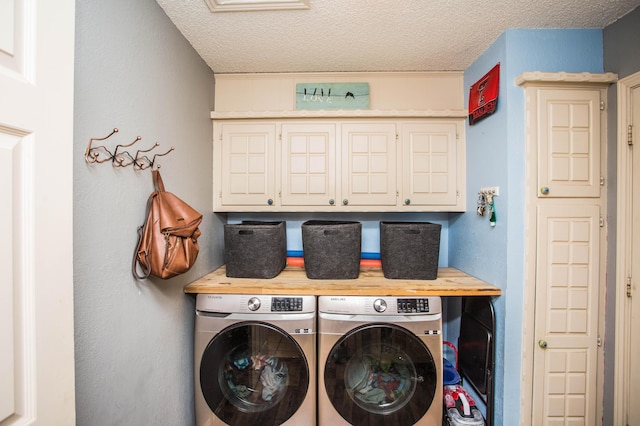 laundry room featuring cabinet space, a textured ceiling, and washer and dryer