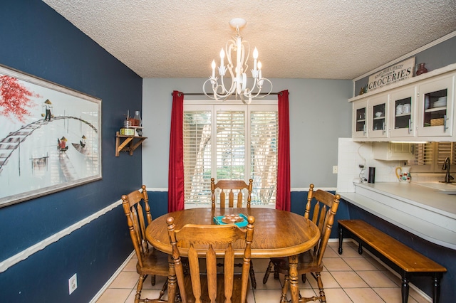 dining area featuring light tile patterned flooring, a textured ceiling, baseboards, and an inviting chandelier