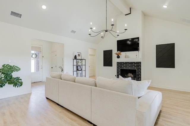 living room featuring a tile fireplace, beam ceiling, high vaulted ceiling, light hardwood / wood-style floors, and a chandelier