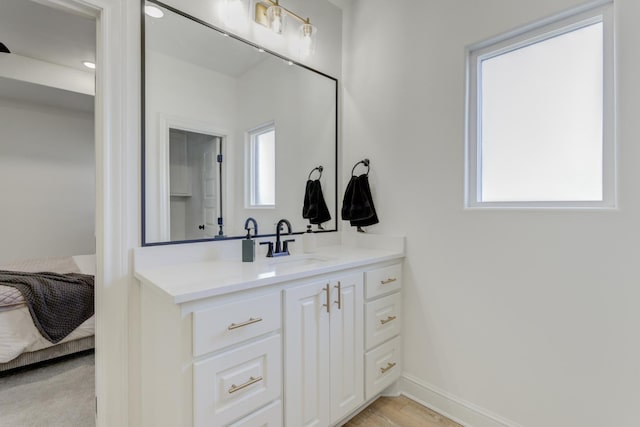 bathroom with vanity, hardwood / wood-style flooring, and a healthy amount of sunlight