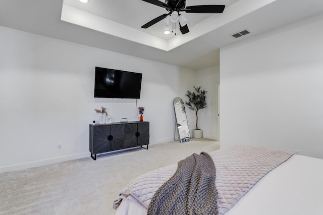 carpeted bedroom featuring ceiling fan and a tray ceiling