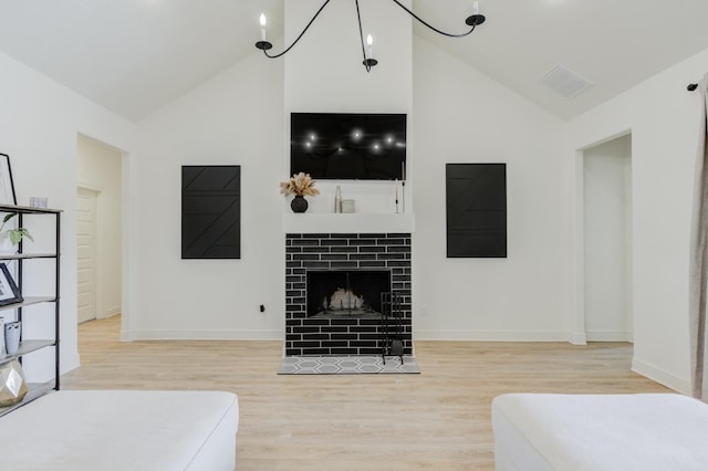 living room with a tiled fireplace, high vaulted ceiling, and light wood-type flooring