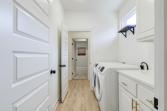 laundry area with light hardwood / wood-style floors, washing machine and dryer, and cabinets